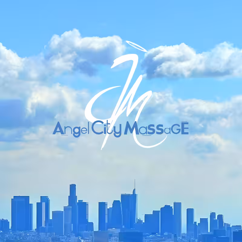 A woman receiving a relaxing facial massage while lying down with eyes closed. Her head is adorned with small pink and white flowers, resting on a white towel. A pink towel covers her shoulders.